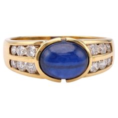 One Vintage Sapphire Diamond 18k Yellow Gold Ring. Featuring one oval cabochon cut sapphire weighing approximately 3.00 carats. Accented by 12 round brilliant cut diamonds with a total weight of approximately 0.60 carat, graded colorless, VS clarity. Crafted in 18 karat yellow gold with purity mark. Circa 1980. The ring is a size 8 ¼ and may be resized. About this Item: Step into timeless elegance with this captivating vintage sapphire and diamond ring. This stunning piece features an enchanting oval cabochon cut sapphire, showcasing a mesmerizing deep blue hue. Its captivating brilliance is further enhanced by twelve sparkling round brilliant cut diamonds, adding even more refinement. Crafted with utmost precision in 18 karat yellow gold, this ring is a true testament to the art of fine j Luxury Heirloom Yellow Gold Sapphire Ring, Hand Rings, Vintage Sapphire, Sapphire And Diamond Ring, Right Hand Rings, Sapphire Diamond Ring, 18k Yellow Gold Ring, European Cut Diamonds, Yellow Gold Ring