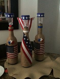 three wine bottles decorated with american flags on top of a table in front of a mirror