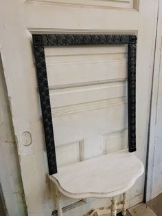 an old white chair sitting in front of a door with black trim on the frame