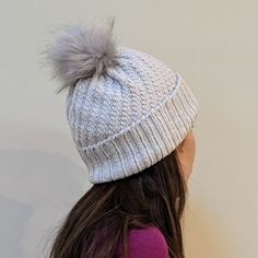 a woman wearing a white hat with a gray pom - pom