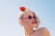 a woman wearing sunglasses and a flower in her hair is looking off into the distance