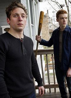 two young men standing on a porch holding baseball bats and looking at the camera man