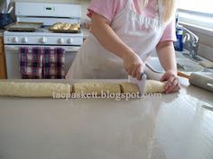 a woman in an apron rolling dough on a counter