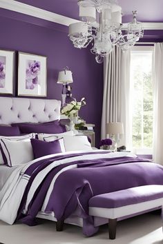 a purple and white bedroom with chandelier, bed, pillows and pictures on the wall