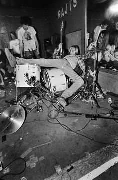 a man laying on top of a drum kit in front of a group of people