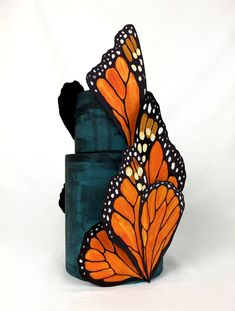 an orange and black butterfly sitting on top of a blue box with its wings open