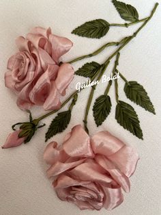 two pink roses with green leaves on a white cloth background and the words quilting bliss written in cursive writing