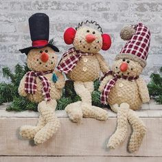 three teddy bears wearing hats and scarves are sitting on a ledge in front of a brick wall