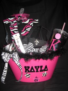 a pink basket with zebra print and personal items in it on a black cloth background