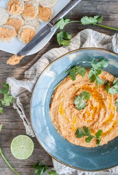 a bowl of hummus with cilantro and tortilla chips on the side