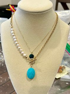 This stylish and elegant necklace effortlessly blends the timeless allure of pearls with the sleek sophistication of a gold chain. The addition of a large natural turquoise pendant adds a unique, eye-catching element that elevates its charm. Perfect for both everyday wear and special occasions, this necklace is a versatile accessory that enhances any fashionable outfit. **Description** * Rolo Chain: 14K gold plated on brass * Freshwater pearls, 6~7mm, button shaped * Gemstone turquoise pendant, Elegant Turquoise Pearl Necklace, Turquoise Necklace With Pearl Drop As Gift, Elegant Double Strand Turquoise Necklace, Turquoise Necklace With Pearl Drop For Gift, Elegant Turquoise Pearl Drop Necklace, Gift Turquoise Necklaces With Pearl Chain, Elegant Turquoise Necklace With Pearl Chain, Elegant Turquoise Chain Necklace Gift, Elegant Turquoise Necklace With Pearl Drop