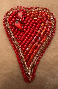 a red beaded heart hanging on a wall