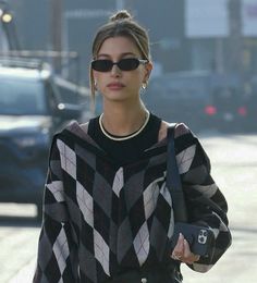 a woman in black and white sweater walking down the street with her hand on her hip