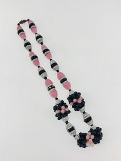 two black and white beads with pink flowers on them are hanging from a necklace that is made out of glass beads