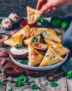 a plate full of pita bread with sauce and herbs on the table next to it