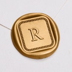 the letter r is inscribed in gold on a white surface