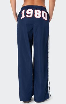 These Edikted 1980 Nylon Track Pants offer both style and comfort, making them perfect for a sporty yet fashionable look. They're ideal for any activity, ensuring you feel comfortable and confident throughout your entire day. Track pantsLace stripe detailingSlitted hemAdjustable waist tieEmbroidered graphic textPolyesterModel wears size SModel height is 5'8Item care: Machine wash at maximum 30C, wash with similar colors, do not bleach, do not tumble dry, iron at a maximum of 110C, do not dry clean. Edikted Womens 1980 Nylon Track Pants - Blue size XL Sweatpants With Words On Back, Extra Long Pants, Sporty Fits, White Track Pants, Aesthetic Pants, Cool Sweatpants, Vintage Sweatpants, Nylon Track Pants, Graphic Sweatpants