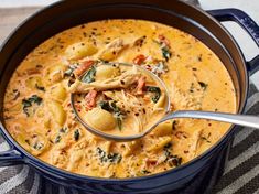 a ladle full of pasta and spinach in a blue pot with a spoon