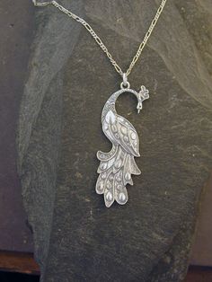 "This Peacock Bird pendant is Sterling Silver. The included chain is a Sterling Silver Figaro 50 chain. You may choose 16, 18 or 20 inch at the same price. Other length available at sightly higher prices. This Peacock Bird pendant measures 2 3/8\" tall by 7/8\" across. I hand cast all my pieces using the lost wax casting method. Please ask your needs. You may call me with questions, often I am out so please use my machine. 831-476-3176. Satisfaction Guaranteed! I send items USPS First Class unle Sterling Silver Necklace With Peacock Design, Silver Peacock Pendant Necklace, Elegant Silver Necklace With Peacock Design, Elegant Peacock Pendant Necklace, Peacock Design Pendant Necklace Gift, Peacock Design Pendant Necklace As Gift, Elegant Peacock Color Pendant Necklace, Elegant Silver Jewelry With Peacock Design, Elegant Peacock Design Necklace For Gift