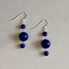 These earrings are made of sterling silver wire and two sizes of round Lapis Lazuli stones. Measuring two (2) inches long, these earrings are a nice addition to any outfit. The sterling silver ear hooks on these earrings are perfect for even the most sensitive ears. These earrings make a great gift and gift wrapping comes standard with any purchase. A little bit about the gemstone used in this piece: Lapis Lazuli encourages self-awareness, allows self-expression and reveals inner truth, providin Sterling Silver Jewelry With Round Beads And Ear Wire, Sapphire Dangle Earrings In Sterling Silver, Sapphire Sterling Silver Dangle Earrings, Blue Round Stone Earrings For Gift, Silver Lapis Lazuli Dangle Earrings, Silver Lapis Lazuli Drop Earrings, Nickel-free Round Silver Plated Wire Jewelry, Hypoallergenic Sapphire Round Earrings, Nickel-free Sterling Silver Round Bead Jewelry