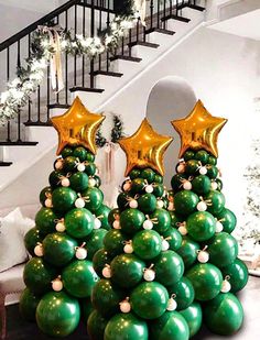 christmas tree made out of balloons in front of stairs with garlands and stars on them