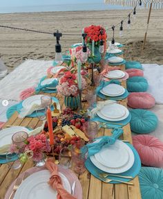 a table set up with plates and place settings for an outdoor dinner on the beach