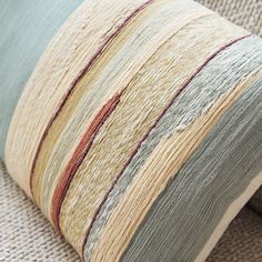 a close up of a pillow on a couch with a beige and blue stripe pattern