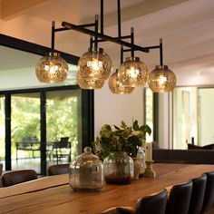 a wooden table topped with vases filled with water and lights hanging from it's ceiling