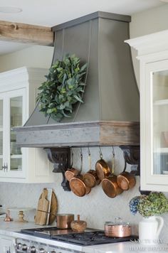 a stove top oven sitting inside of a kitchen next to wooden utensils and pots