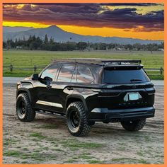 a black truck parked on top of a dirt field