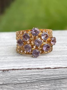 Unique 18 karat Yellow Gold Harem Stacking Ring featuring sparkly synthetic color changing sapphires (purple to turquoise color change) and diamonds METAL: 18 karat SIZE: 6 - sizing is not recommended due to nature of ring ERA: 1960s/1970s CONDITION: good vintage condition - stones securely set Kennedy's Cache sells curated antique and vintage pieces. Most have been preowned and loved and will have some signs of age and wear. We will disclose any flaws that would be out of the ordinary for age o Purple Diamond Jewelry With Rose Cut Diamonds, Purple Diamond Jewelry With Rose Cut, Gold Amethyst Rings With Rose Cut Diamonds, Amethyst Diamond Ring With Rose Cut Diamonds For Anniversary, Purple Sapphire Multi-stone Ring With Diamonds, Gold Amethyst Ring With Rose Cut Diamonds For Anniversary, Gold Multi-stone Diamond Amethyst Ring, Gold Multi-stone Amethyst Diamond Ring, Gold Diamond Multi-stone Amethyst Ring