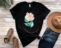 This Watercolor Rose T Shirt is great for spring, summer, fall or anytime you need an artistic reminder to stay positive, grow and shine! The design features a whimsical watercolor rose flower. Purchase for yourself or as a gift for your favorite gardener, flower lover or nature lover. This classic unisex jersey short sleeve tee fits like a well-loved favorite. Soft cotton and quality print make users fall in love with it over and over again. These t-shirts have-ribbed knit collars to bolster shaping. The shoulders have taping for better fit over time. Dual side seams hold the garment's shape for longer.  .: 100% Airlume combed and ringspun cotton (fiber content may vary for different colors) .: Light fabric (4.2 oz/yd² (142 g/m .: Retail fit .: Tear away label .: Runs true to size ABOUT T Watercolor Rose Flower, Flower T Shirt, Floral T Shirt, Whimsical Watercolor, Rose Shirts, Rose T Shirt, Stay Positive, Watercolor Flower, Watercolor Rose