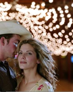 a man and woman standing next to each other in front of a string of lights