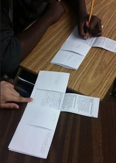 two people sitting at a table with papers and pencils on top of the desk