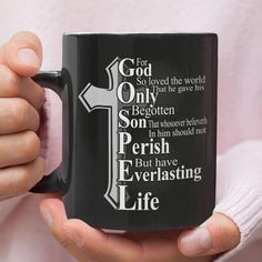 a person holding a black coffee mug with the words for god so loved the world