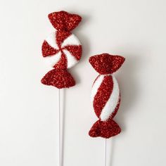 two red and white candy lollipops on top of each other in the shape of bows