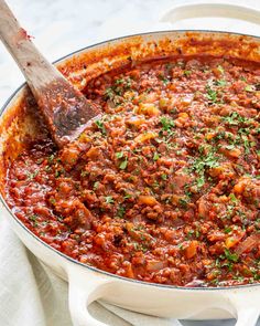 a large pot filled with food and a wooden spoon on top of the pot full of it