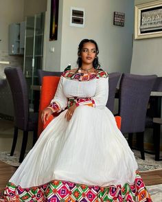 a woman sitting on top of a chair in a white dress