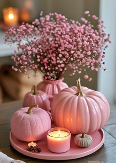 pink pumpkins and candles are on a plate with flowers in the center, along with small baby's breath