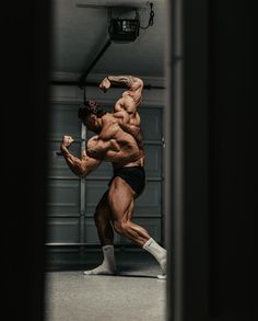 a bodybuilding man flexing his muscles while standing in front of a garage door