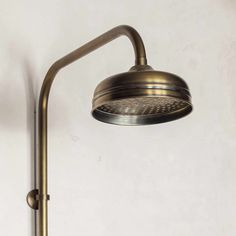 an antique brass shower head and arm on a white wall