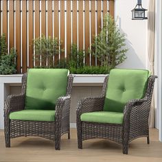 two wicker chairs sitting next to each other in front of a planter and window