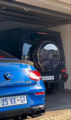 two cars are parked in the garage with their doors open and there is a mercedes benz logo on the door