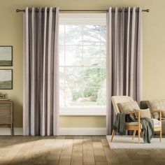 a living room filled with furniture and a window covered in striped drapes next to a chair