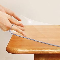 a person using a knife to cut through a piece of paper on top of a wooden table