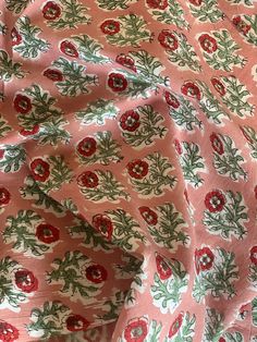 the fabric has red flowers and green leaves on it, as well as an orange background