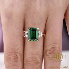 a woman's hand with a ring on it and an emerald in the middle