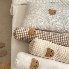 three pillows with teddy bears on them sitting next to each other in front of a bed