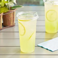 two cups filled with lemonade sitting on top of a table