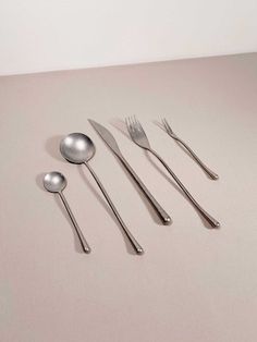 five spoons, two forks and one knife on a table